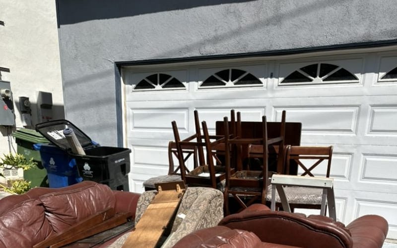 Leather sofa, chaise and wooden dining chairs set out on a Largo driveway for removal