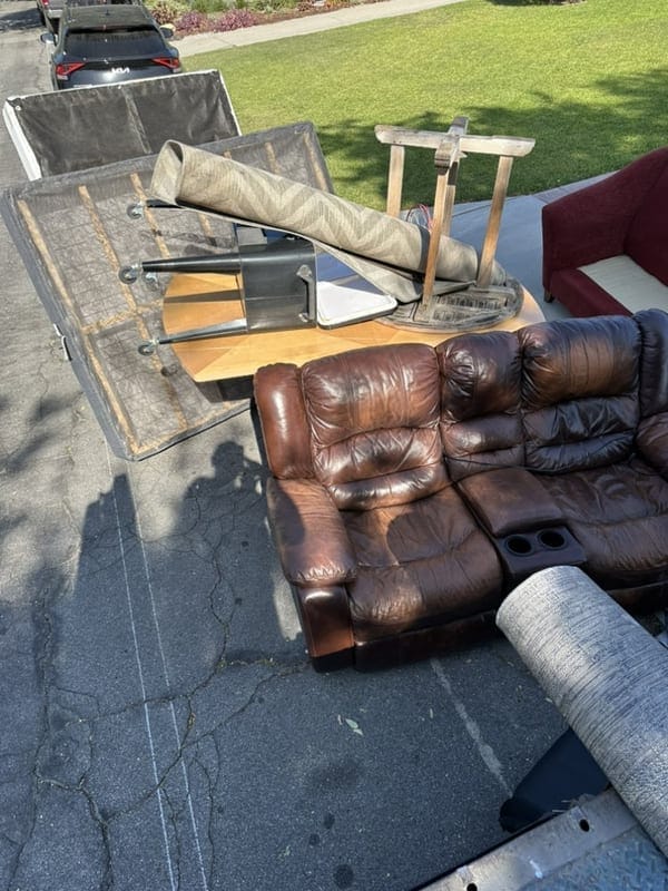 Brown leather sofa, a rolled rug and an office chair set out on a driveway in Largo, FL