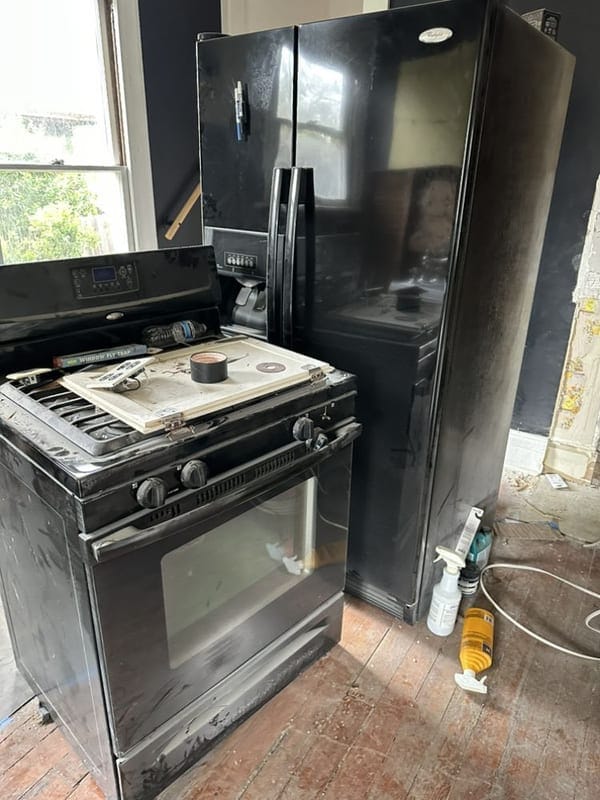 Black refrigerator and gas range disconnected and ready to be carried out of a Largo kitchen