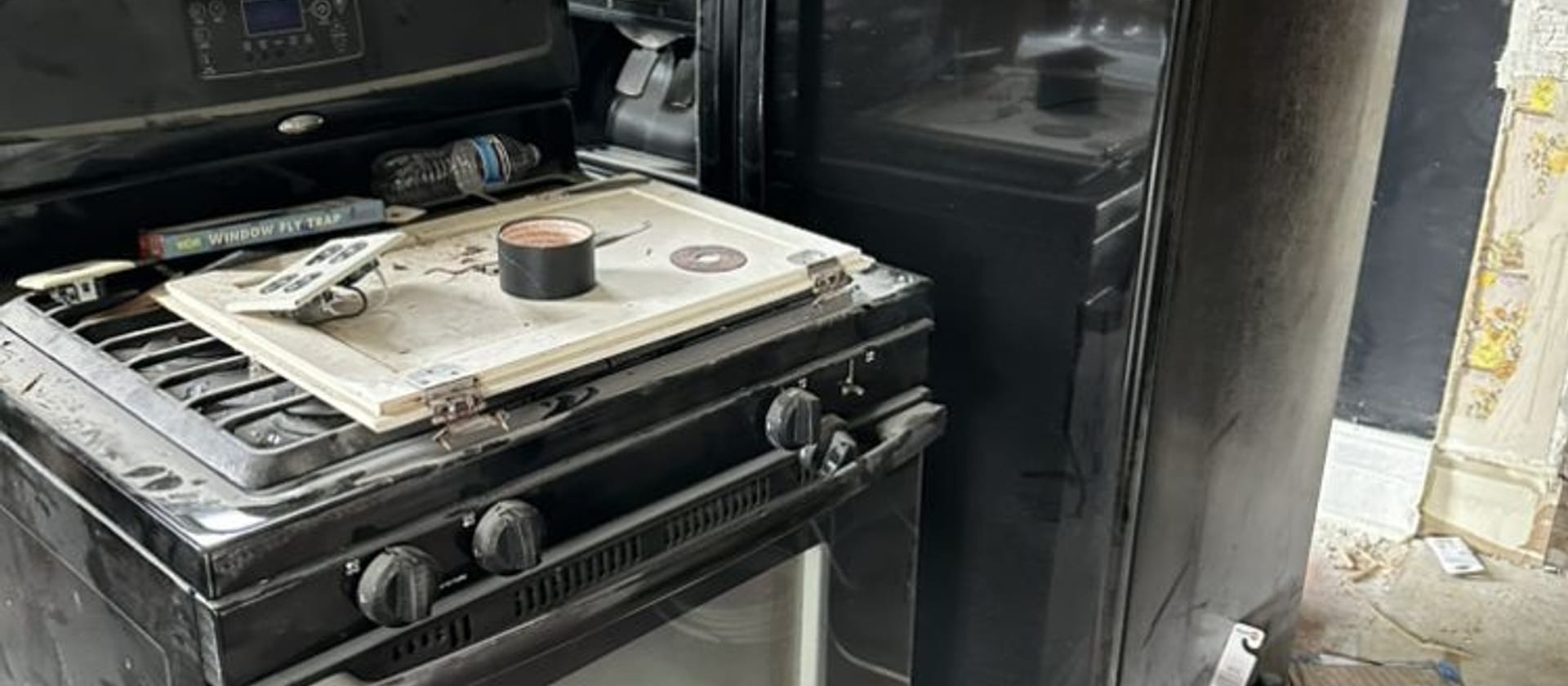 Black refrigerator and gas range pulled out of a kitchen for appliance removal