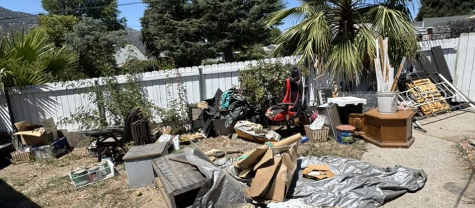 Timber, tarp and storm-blown yard debris spread across a back yard in Largo, FL