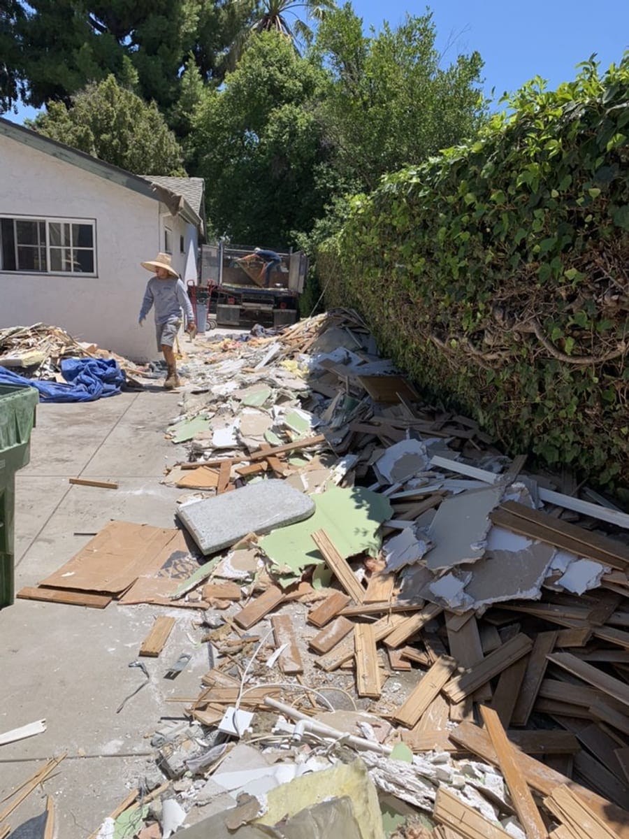 JR Largo crew member beside a long pile of lumber and drywall cleared from a Largo property