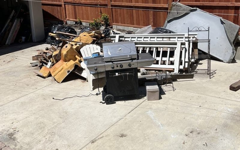 Old grill, metal shelving and white railings cleared from a Largo, FL back yard