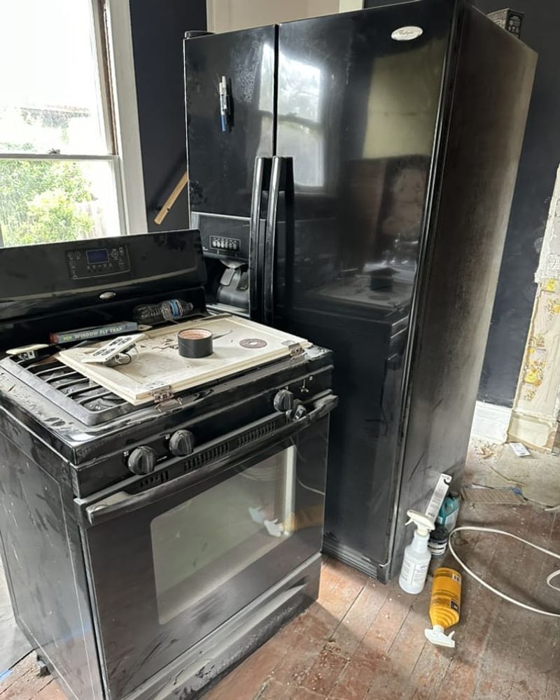 Black refrigerator and gas range disconnected for appliance removal in a Largo, FL kitchen