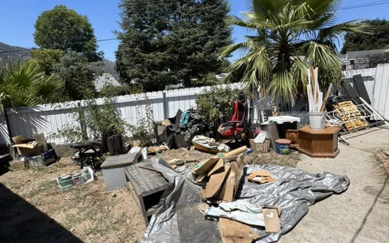 Fallen timber, tarp and yard debris spread across a back yard after a storm in Largo, FL