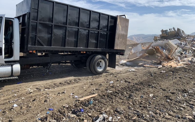 Large open-body hauling truck parked at a commercial clearance site