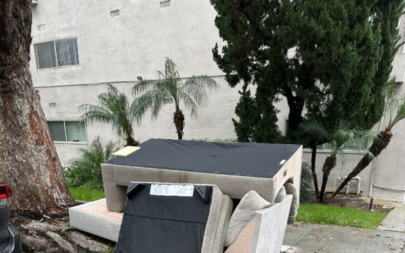 A single sofa and box spring set out at a Largo curb for a one-item pickup