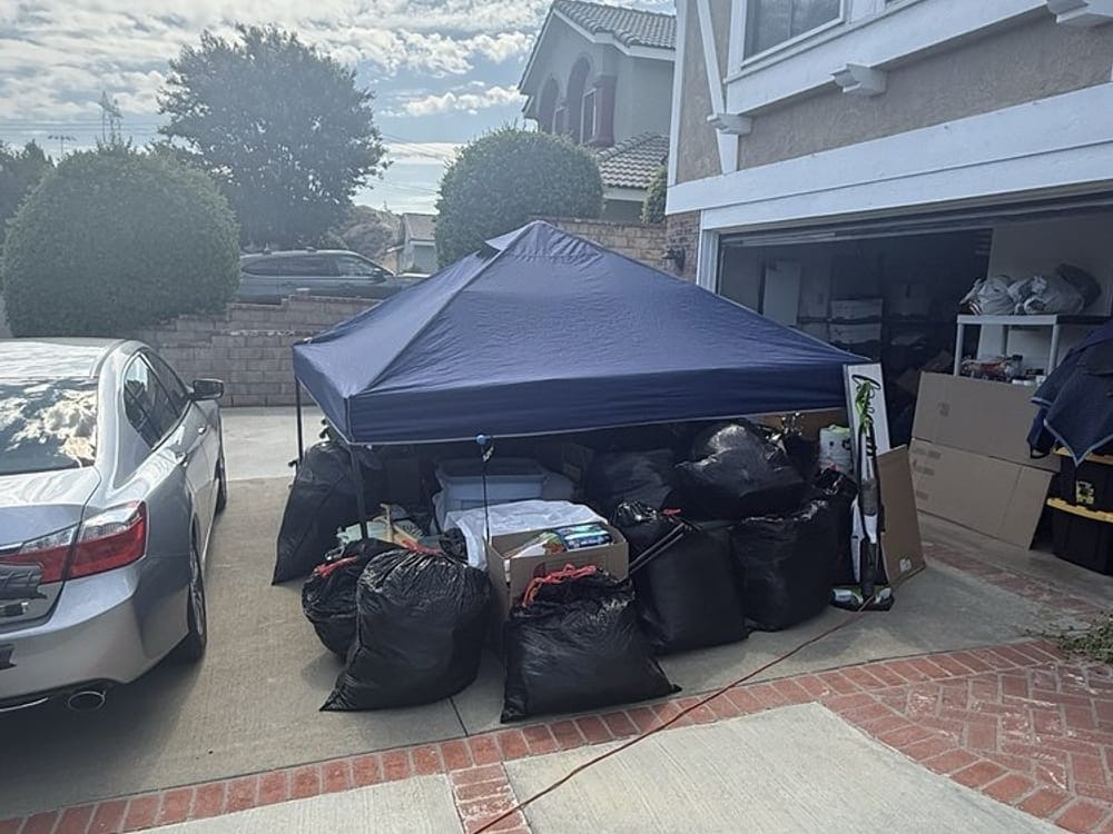 Junk removal under way on a townhome driveway in Largo, FL, bagged waste beside a work canopy
